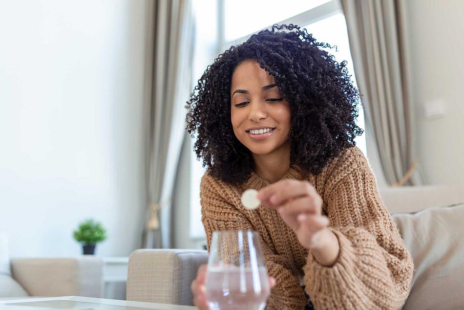 Frau gibt eine Brausetablette in ein Wasserglas