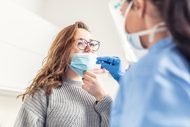 Arzthelferin macht Coronatest bei einer Frau.