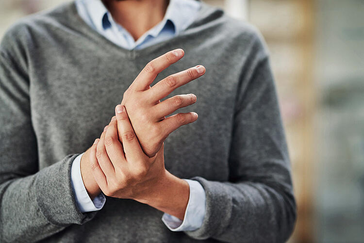 Mann hält sich die schmerzende Hand.