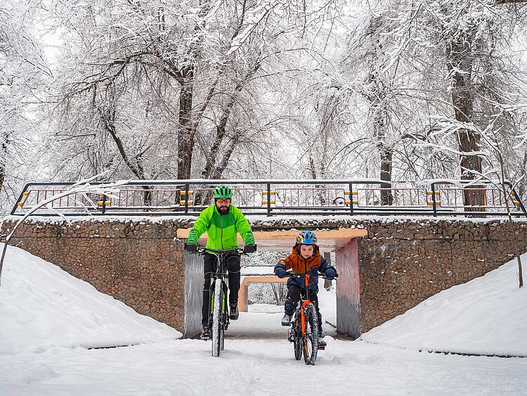 Vater und Sohn fahren im Schnee Fahrrad