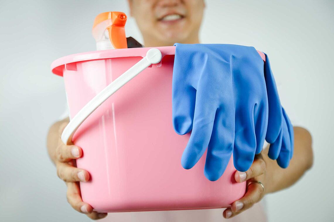 Bildnachweis: © istockphoto.com Mann hält rosa Putzeimer mit ausgestreckten Armen vor dem Körper.