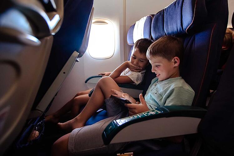 Zwei Jungen im Flugzeug schauen auf ein Tablet