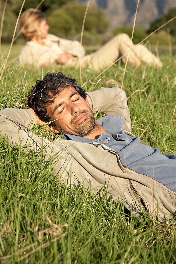 Mann liegt entspannt im Gras.