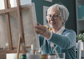 Seniorin malt Bild an einer Staffelei