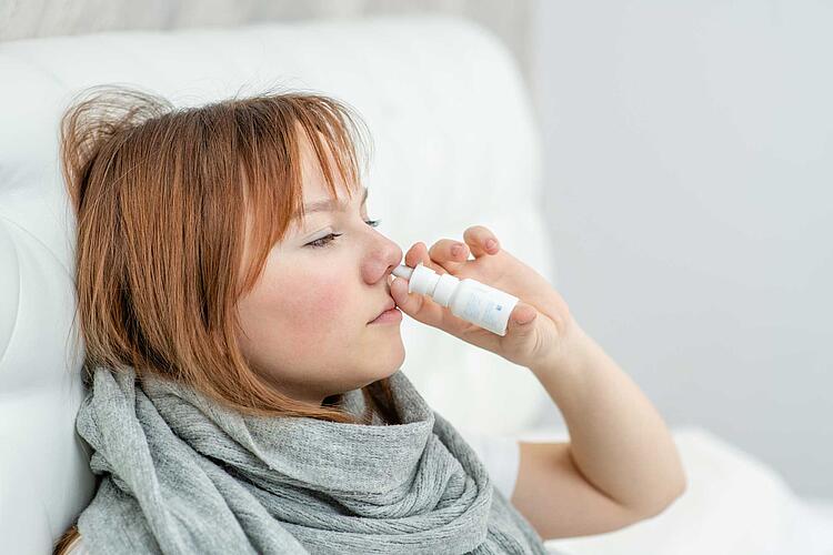 Kranke Frau benutzt Nasenspray
