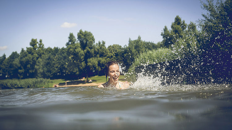Junge Frau schwimmt in einem See.