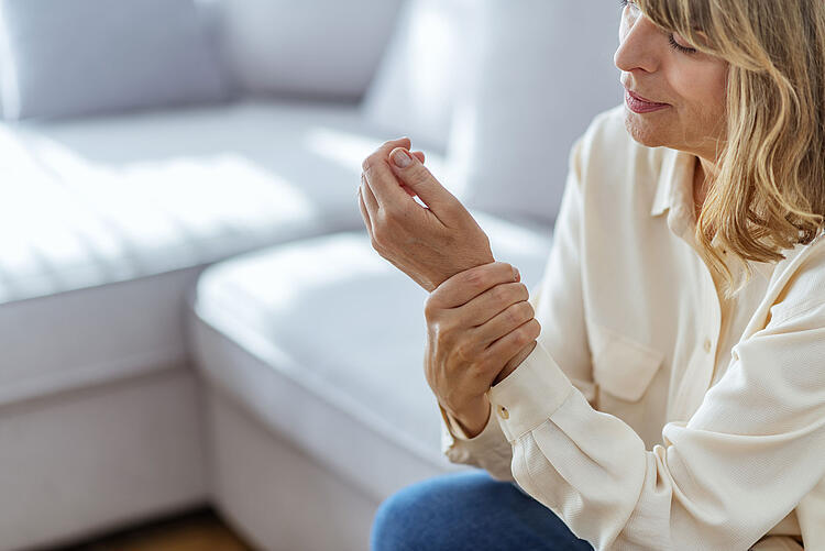 Frau greift sich an ihr schmerzendes Handgelenk