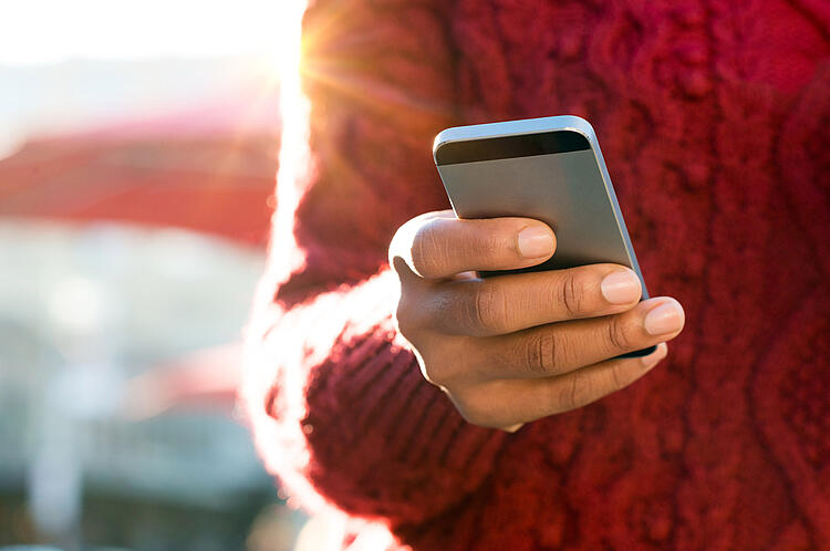 Eine Frau hält ein Handy in der Hand.