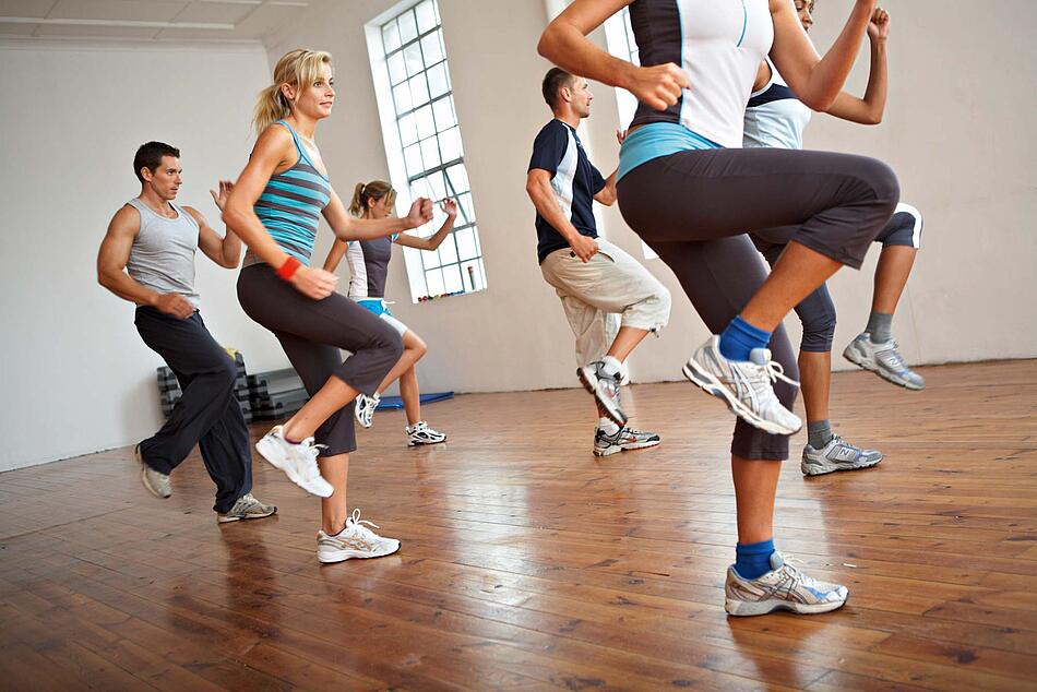 Gruppe macht Aerobicübungen im Fitnessstudio, Anwinkeln des Beins