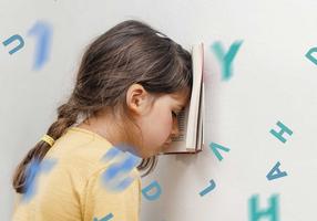 Kinder in der Stressfalle: Mädchen lehnt mit Buch vor der Stirn ihren Kopf an die Wand