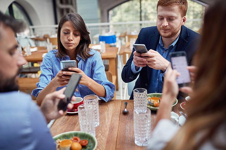 Junge Leute schauen beim Essen auf ihr Smartphone