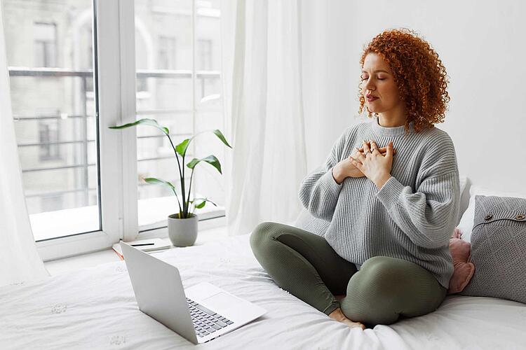 Frau meditiert vor dem Laptop