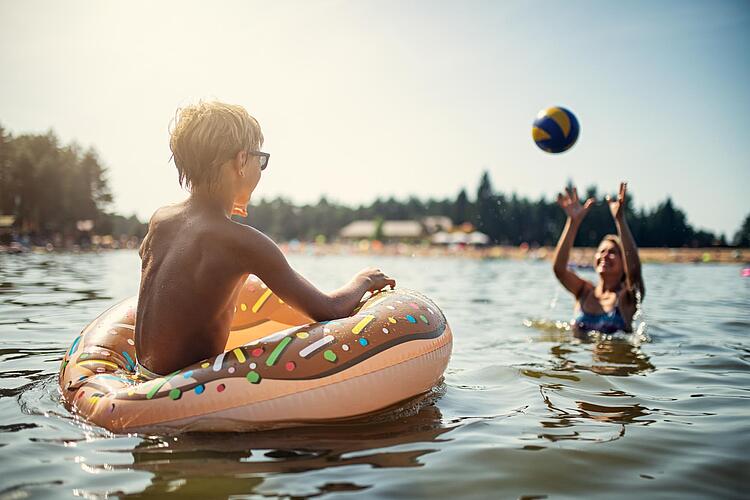 Mutter und Sohn spielen Ball im See