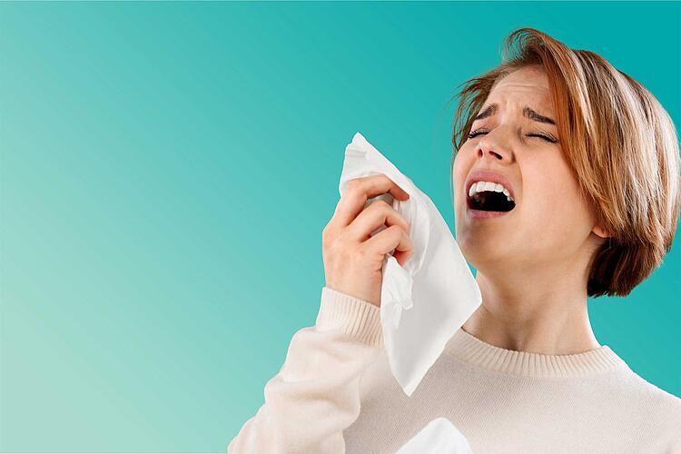 Frau mit Taschentuch in der Hand niest