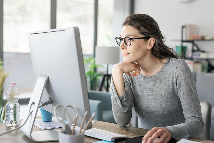 Frau im Büro schaut auf einen Monitor