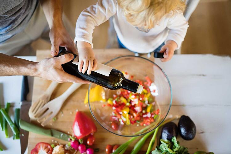 Vater und Kind gießen gemeinsam Öl in einen Salat