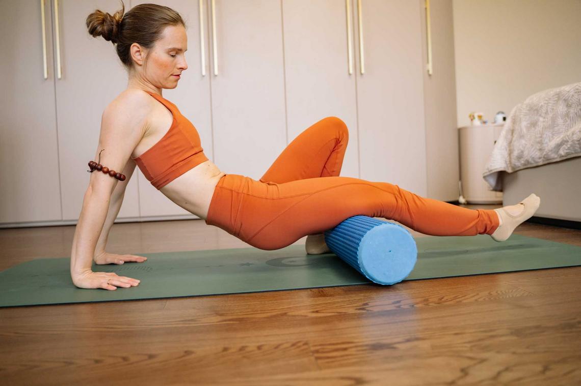 Frau macht Übungen mit der Faszienrolle