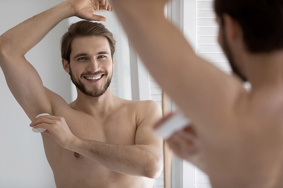 Mann benutzt ein Deodorant.