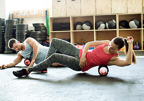 Mann und Frau beim Training mit einer Faszienrolle.