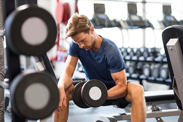 Mann beim Freihanteltraining im Fitnessstudio.