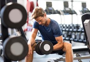 Mann beim Freihanteltraining im Fitnessstudio.