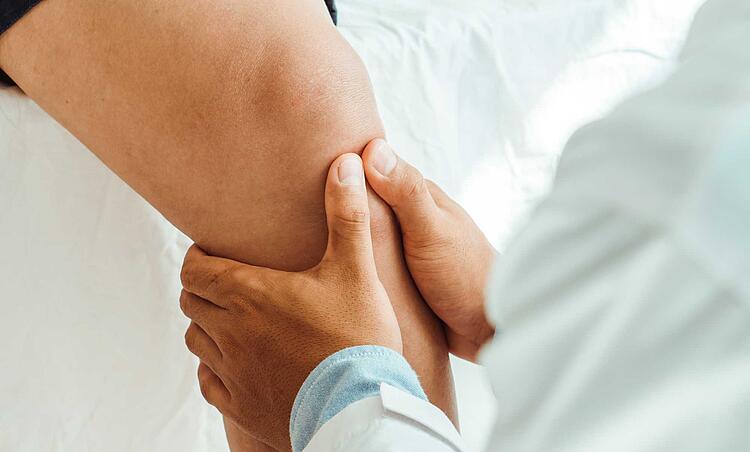 Physiotherapeut behandelt das Knie eines Patienten
