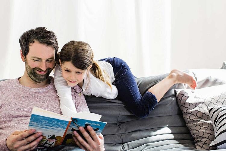 Vater liest Tochter ein Buch vor.