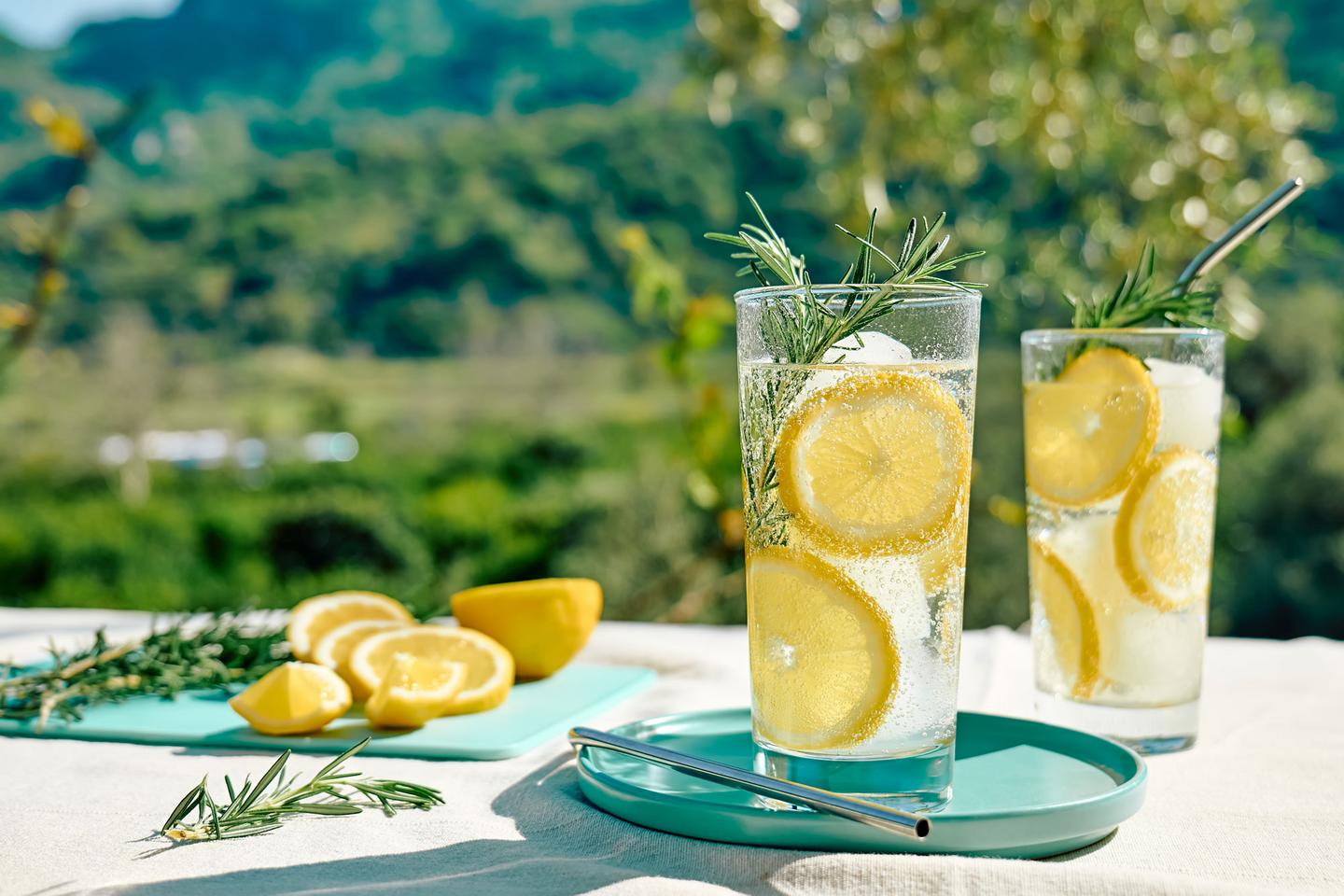 Erfrischende Limonade im Glas mit Zitronenscheiben und Rosmarin