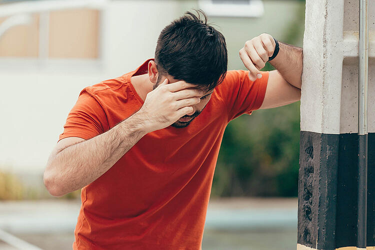 Mann stützt sich an einer Wand ab