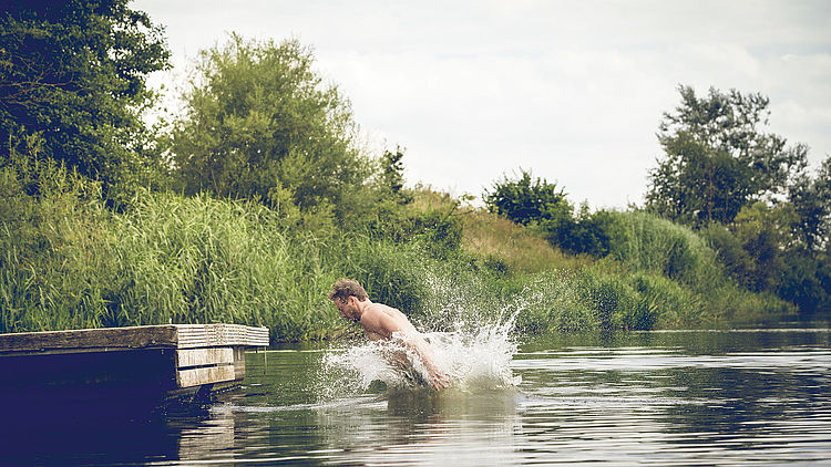 Juger Mann schwimmt in einem See.