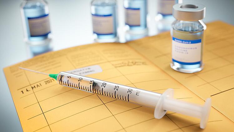 Impfspritze und Impfstoff auf einem Impfpass