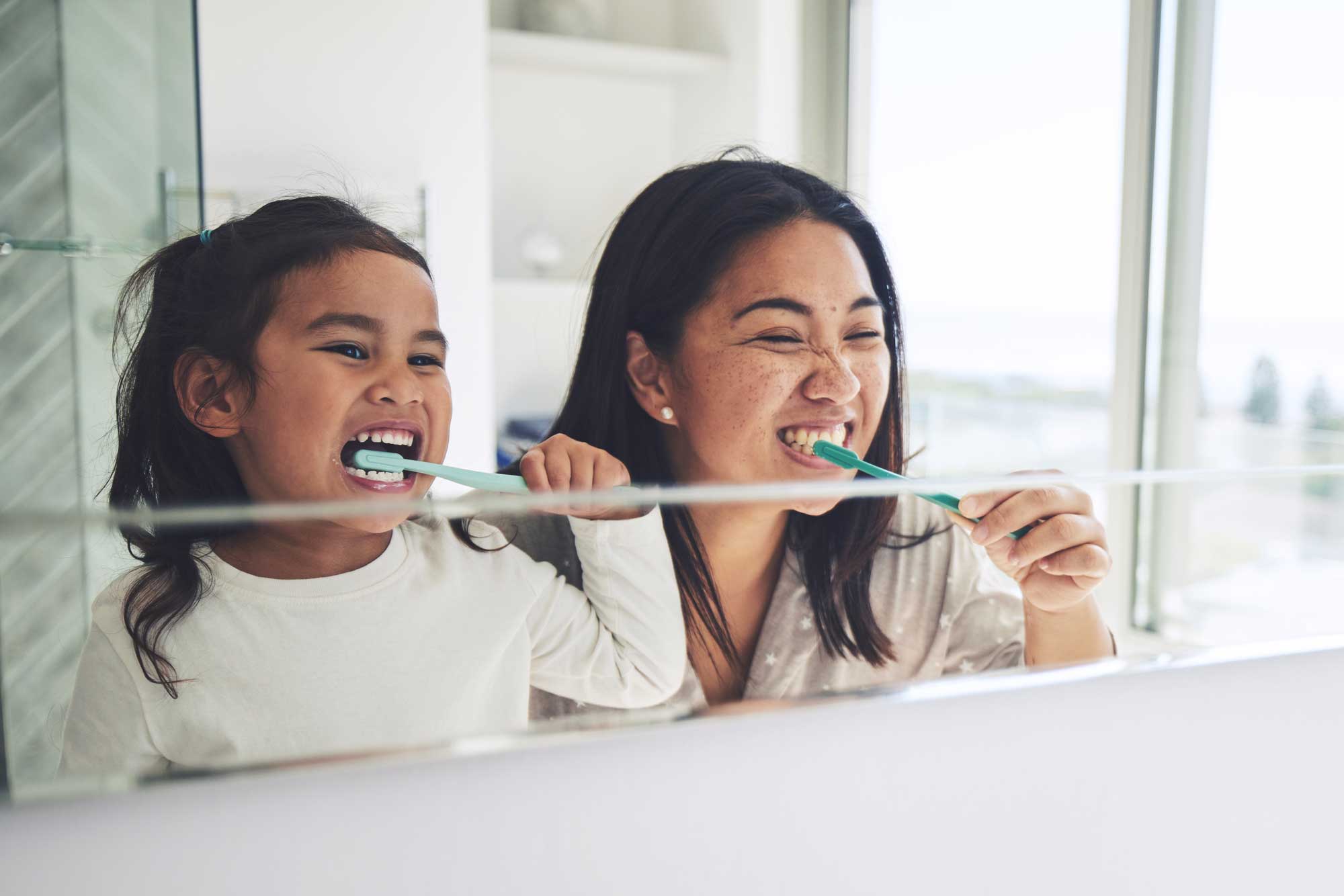 Mutter und Tochter putzen gemeinsam ihre Zähne